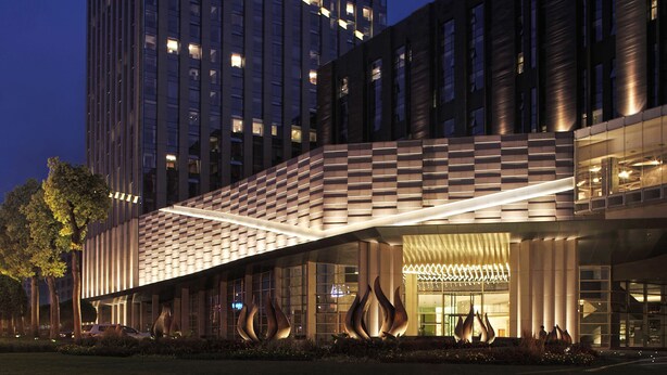 A modern hotel with a prominent tower and a covered entrance. - The Lotus Hotel Chongqing (Chongqing)