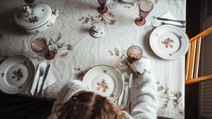 Una mesa de comedor dispuesta con mantel floral, platos, vasos y cubiertos.