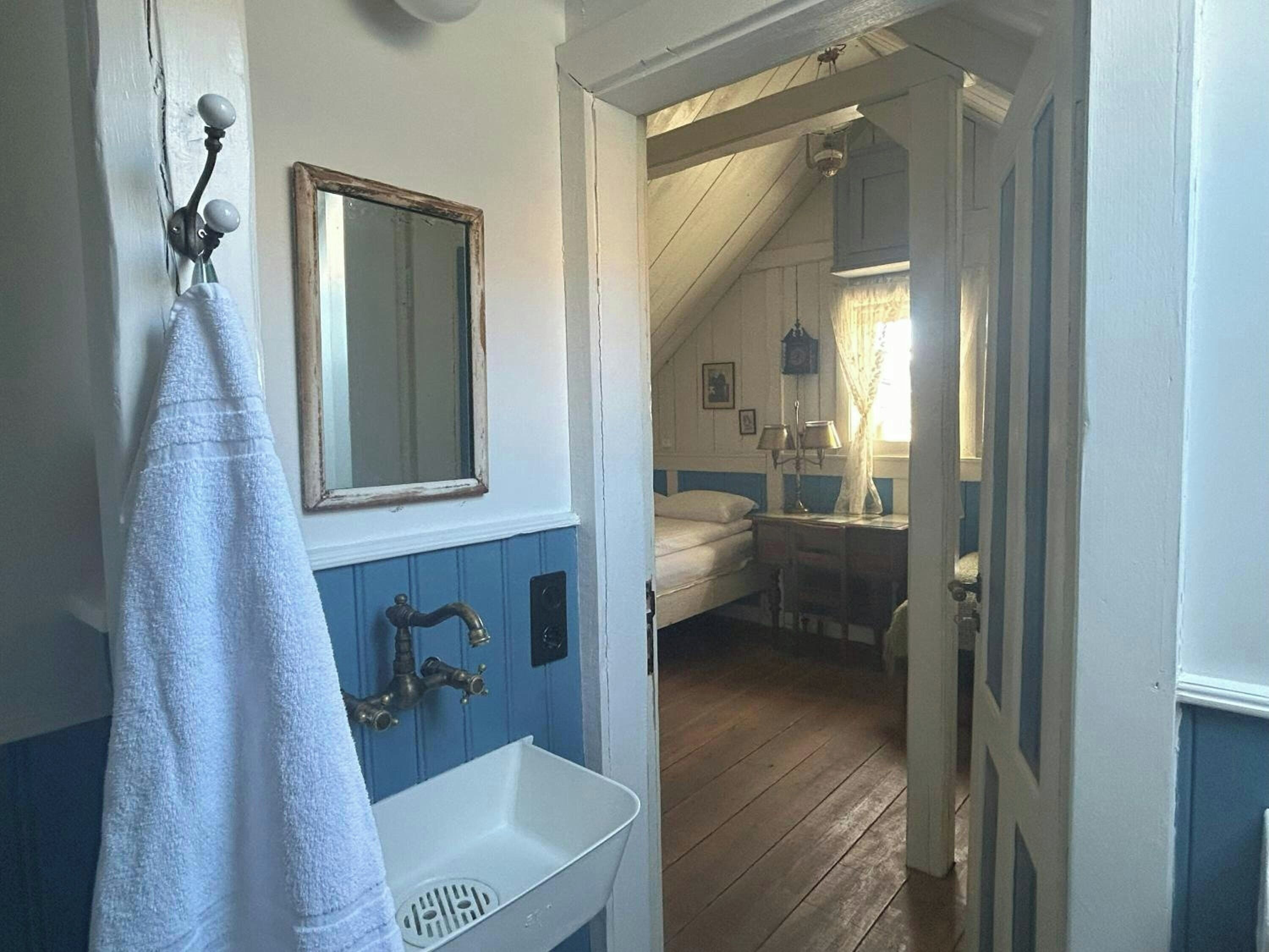 Un baño con un lavamanos blanco, una toalla colgada en la pared y un espejo.
