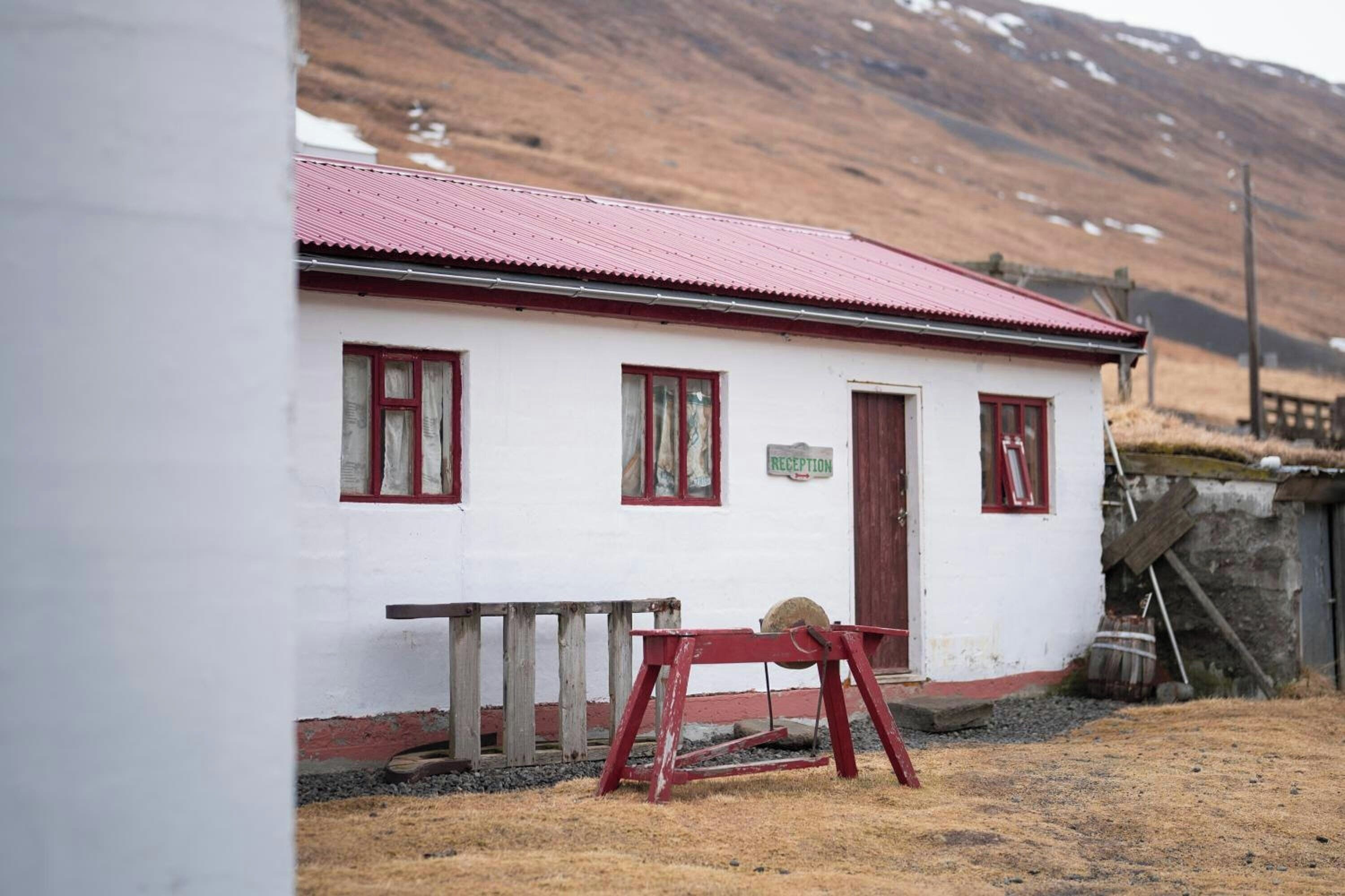 A white building with a red roof and a reception sign.
