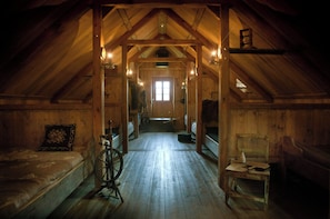 A wooden attic bedroom with a sloped ceiling, a bed, a chair, and a small table.