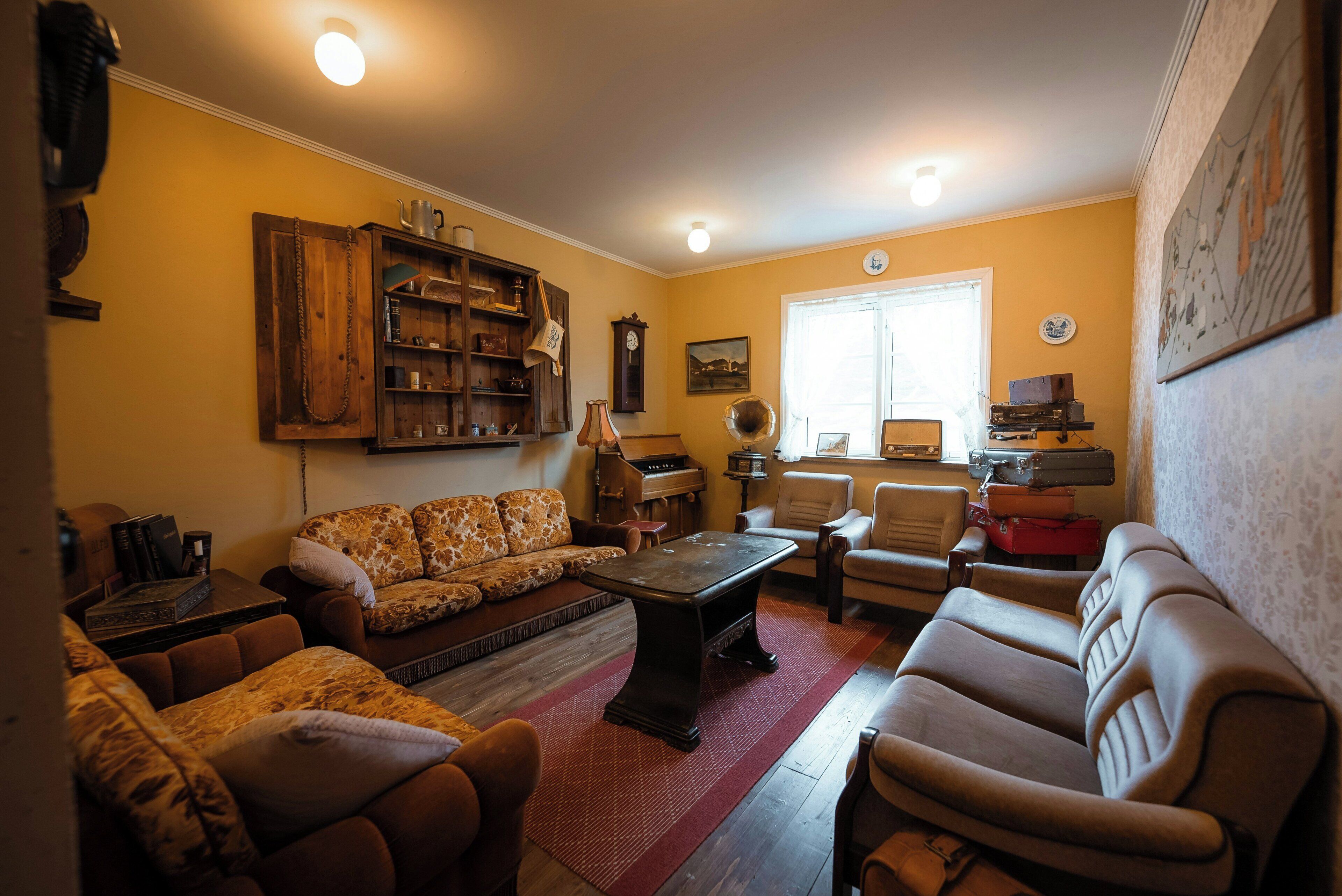A cozy living room with a sofa, armchairs, a coffee table, and a piano.
