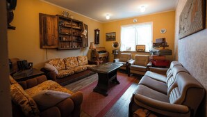 Een gezellige woonkamer met een bank, fauteuils, een salontafel en een piano.