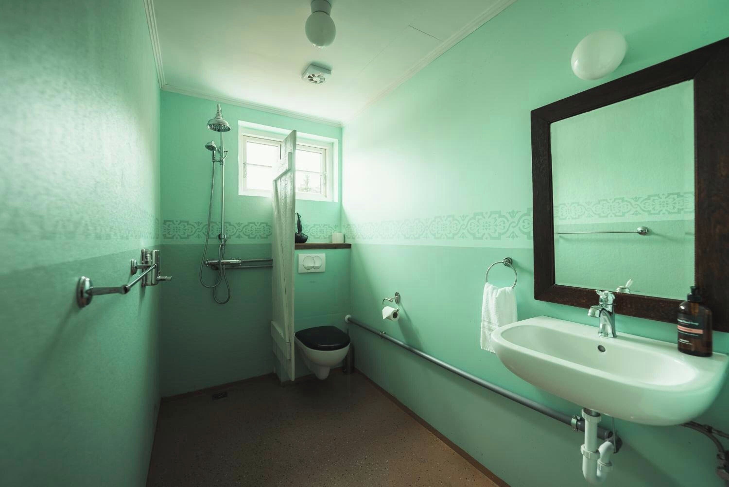 Un baño con inodoro, lavabo, ducha y ventana.