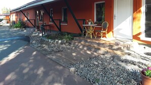 A building with a red exterior, a white door, and a small patio area with a table and chairs.