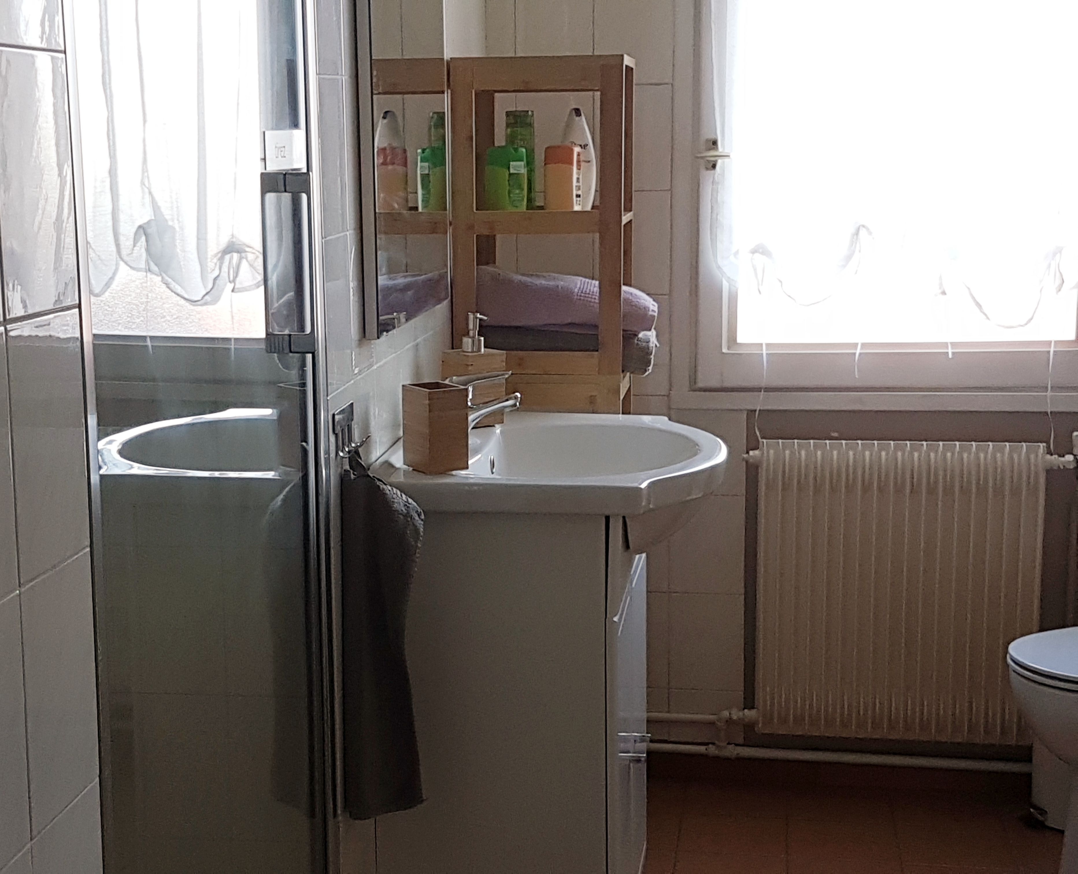 Een badkamer met een wastafel, spiegel en een plank met toiletartikelen.