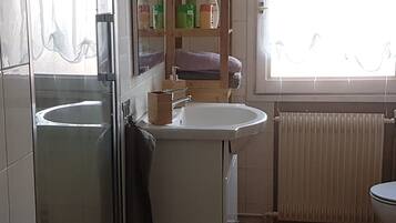 Een badkamer met een wastafel, spiegel en een plank met toiletartikelen.