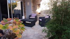 An outdoor patio with stone flooring, two wicker sofas with cushions, a small table, and potted plants. - Ambition Zen Presles (Presles)