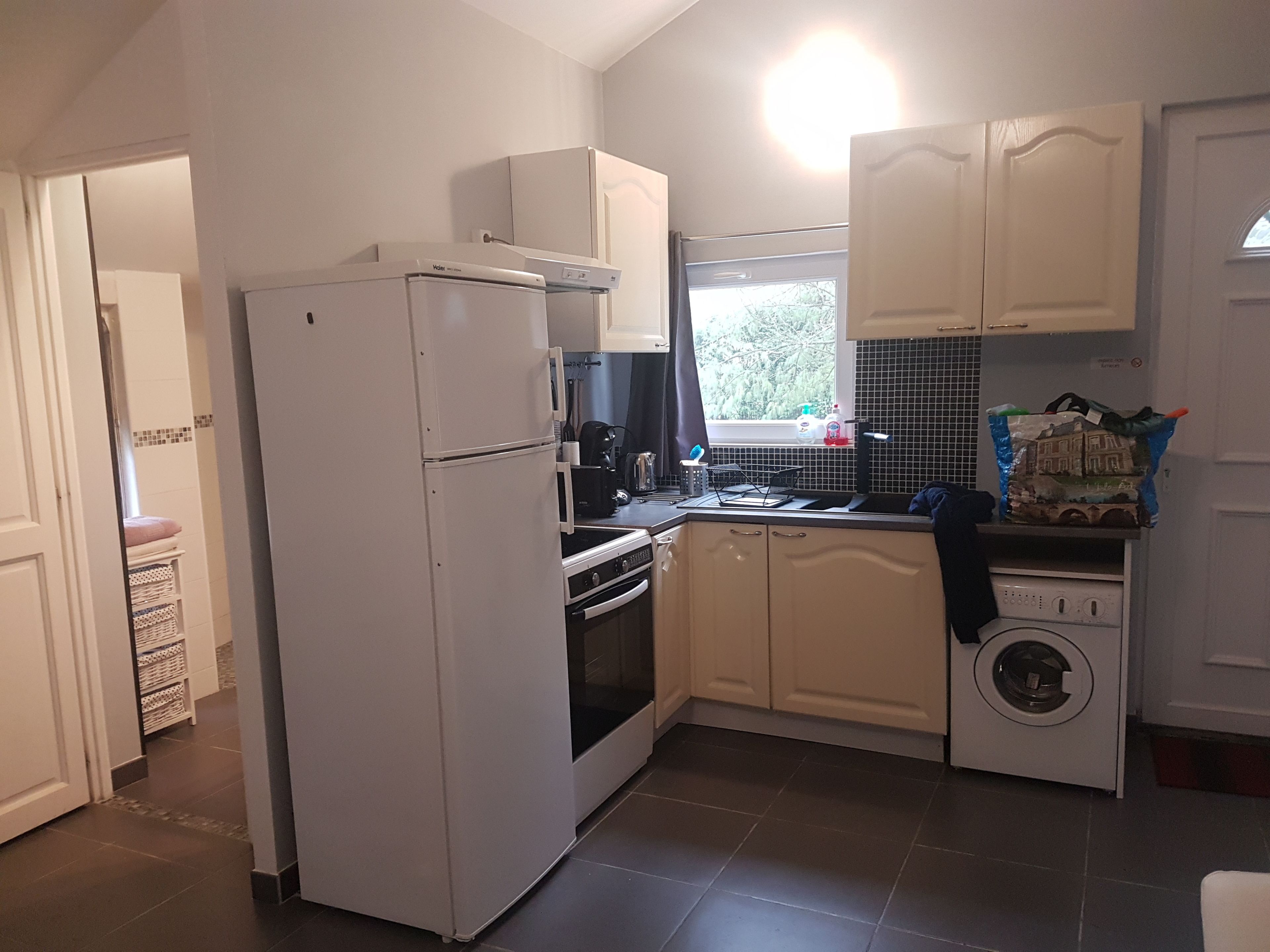 A compact kitchen with a refrigerator, oven, microwave, and a washing machine.