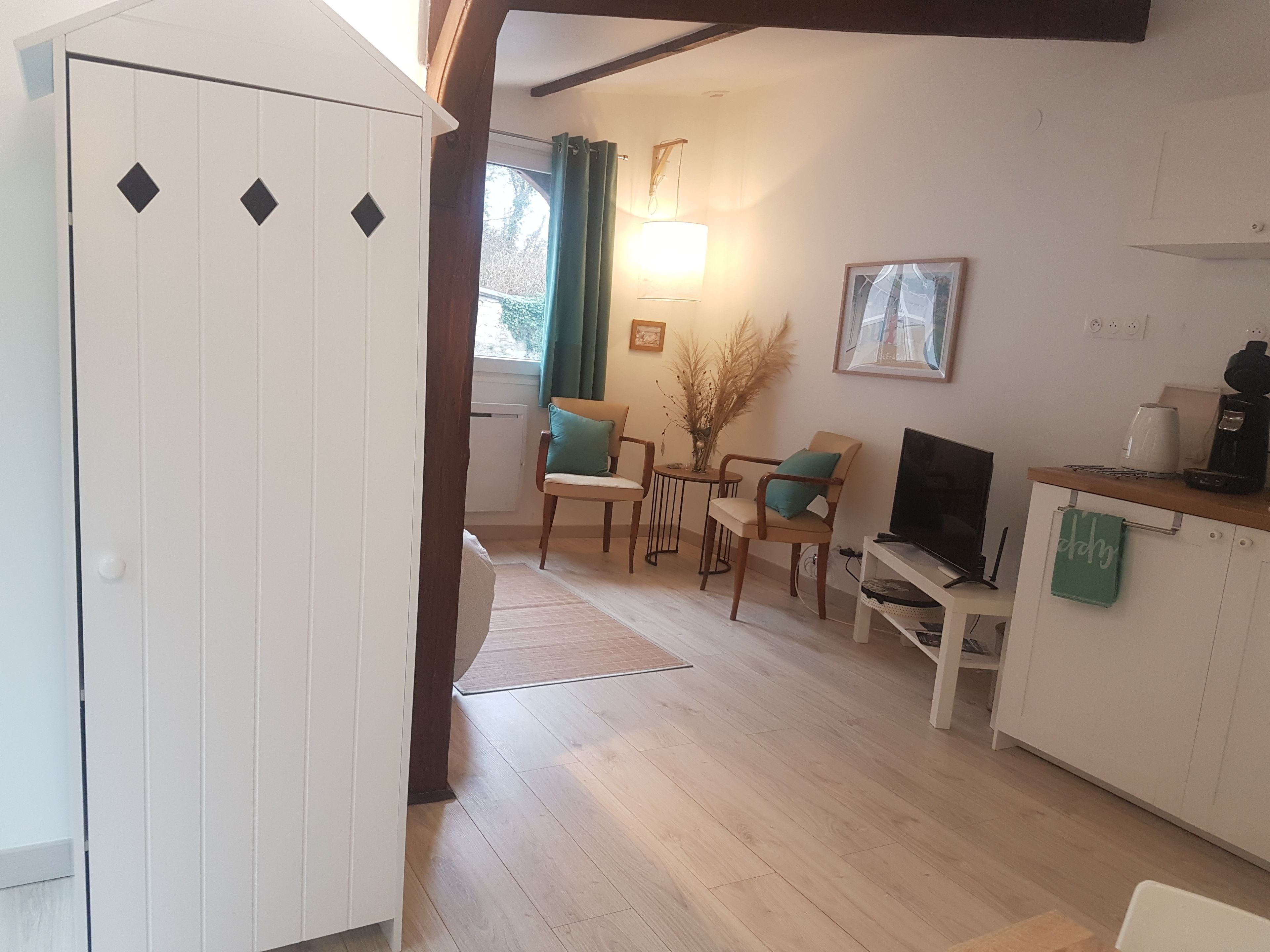 Una cocina moderna con comedor, piso de madera y un armario blanco.