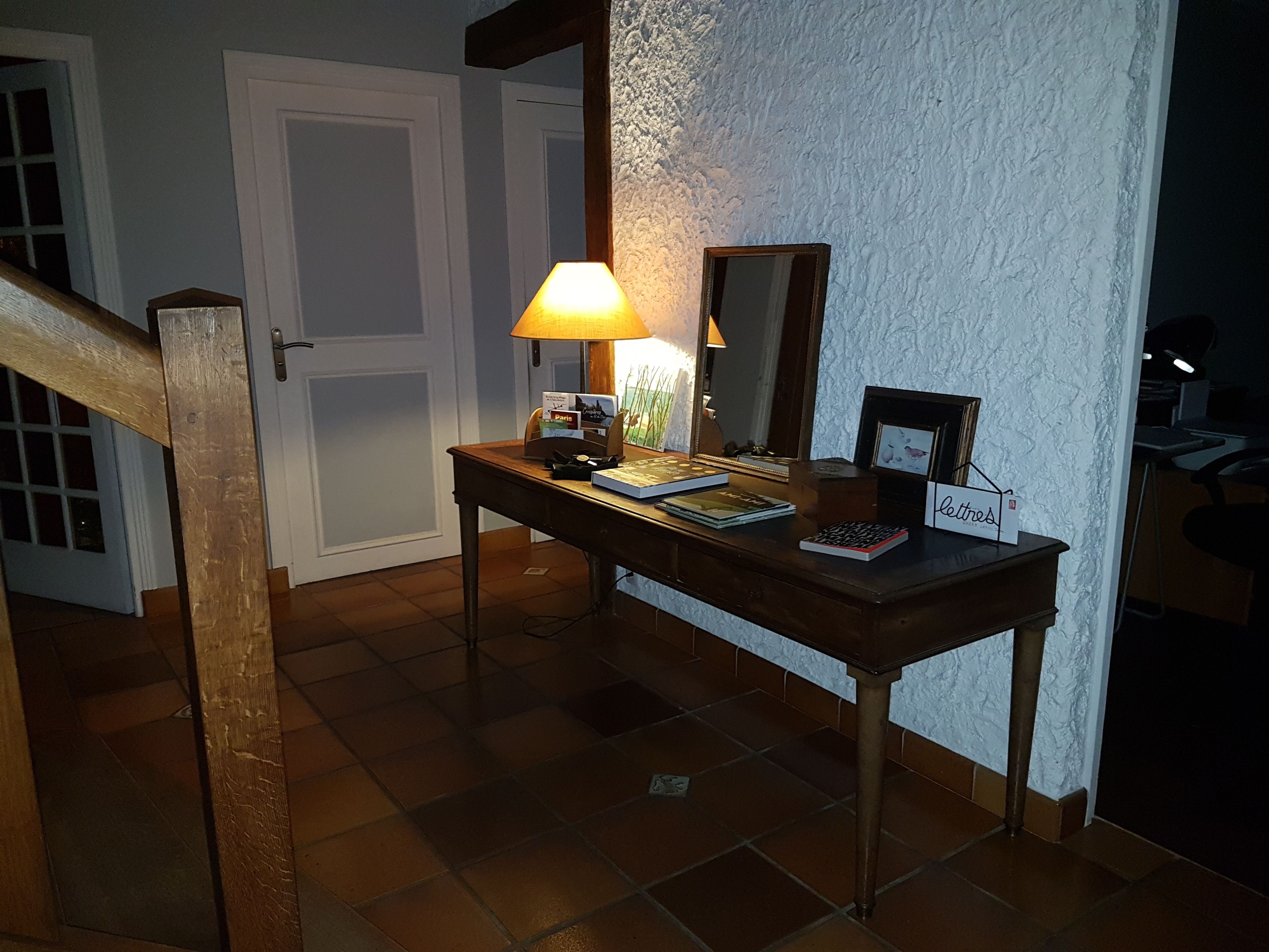 Een houten console tafel met een lamp, boeken, een ingelijste foto en een bord.