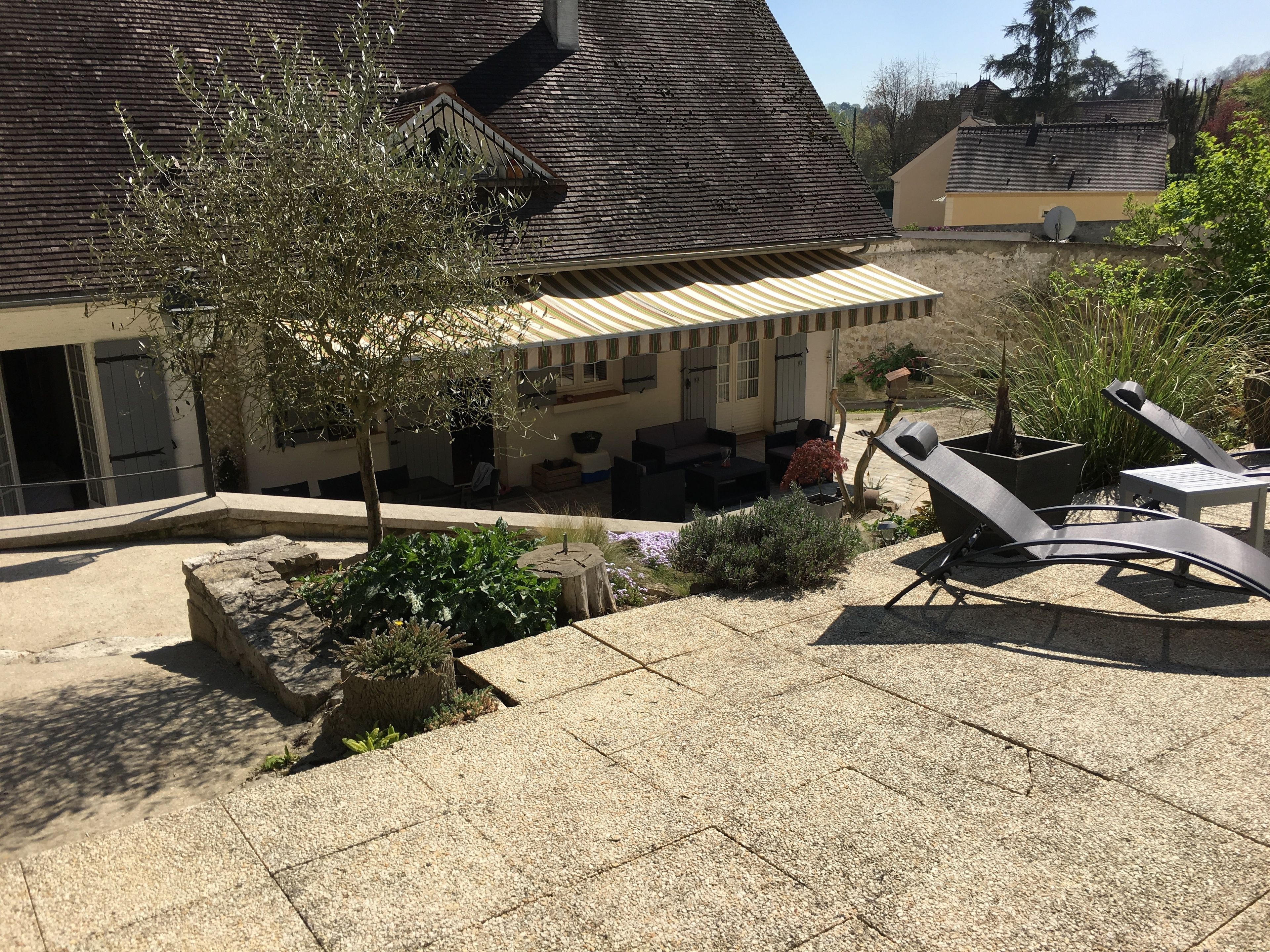 A courtyard with outdoor seating, a tree, and a building with a sloped roof.