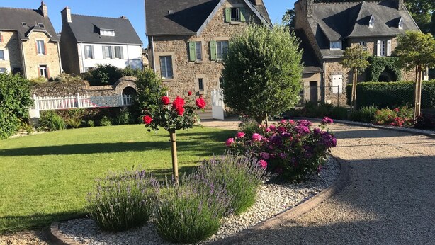 Ein Wohngebiet mit Steinhäusern, einem gepflegten Rasen und Blumenbeeten.
