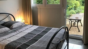 Ein Schlafzimmer mit Bett, Fenster und Blick ins Freie.