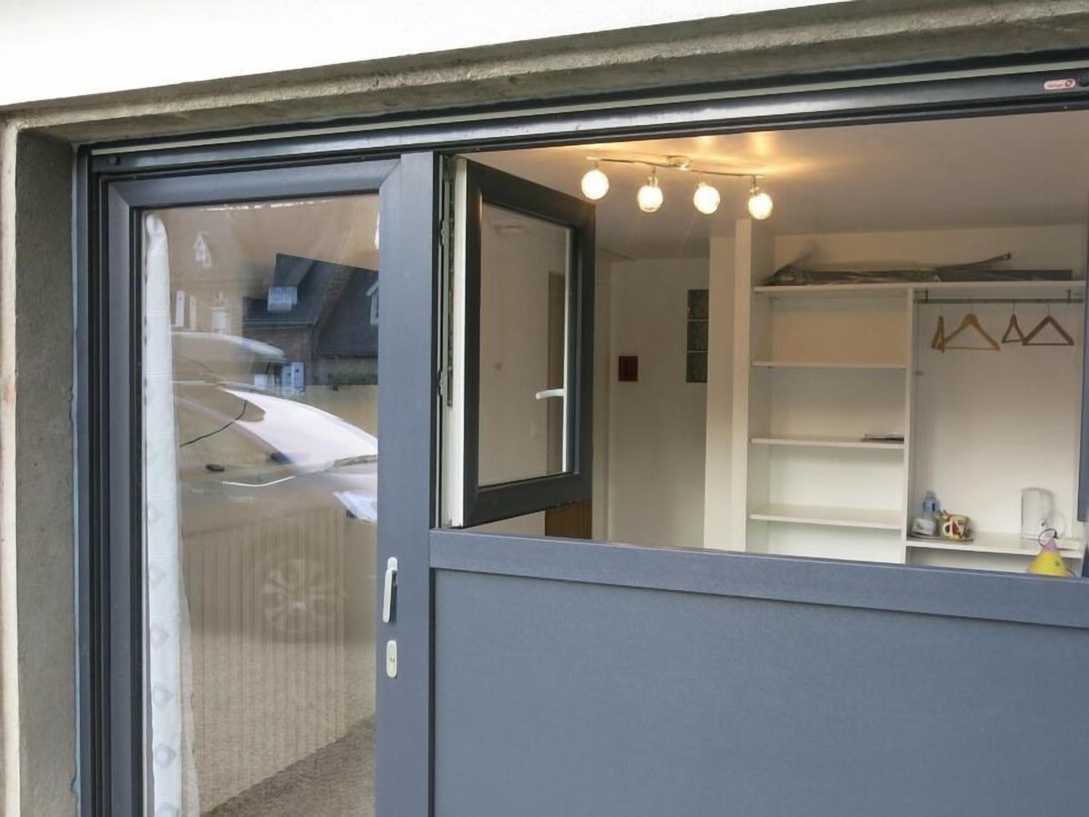 A room with a sliding glass door, a white closet, and a shelf with various items.