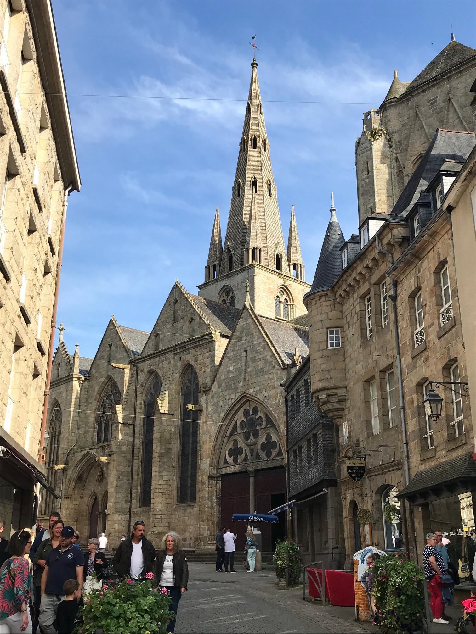 Une église historique, dotée d’un flèche imposante et d’une architecture gothique, entourée de bâtiments en pierre.