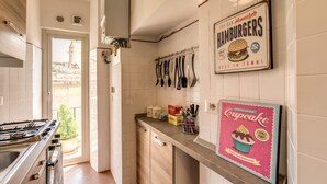 A kitchen with a gas stove, cabinets, and a countertop with a cupcake box and utensils. - Spagna Glamour Life Penthouse (Rome)