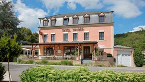 A two-story building with a sign reading "Hotel Gruber". It features a balcony with outdoor seating and a garage. - Hôtel Gruber (Rosport-Mompach)