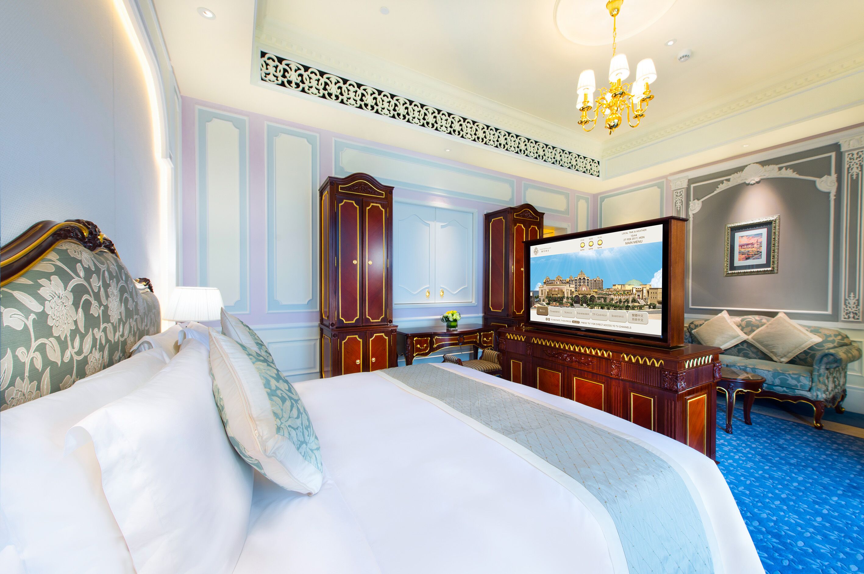 A hotel room with a large bed, a television, and a blue carpet.