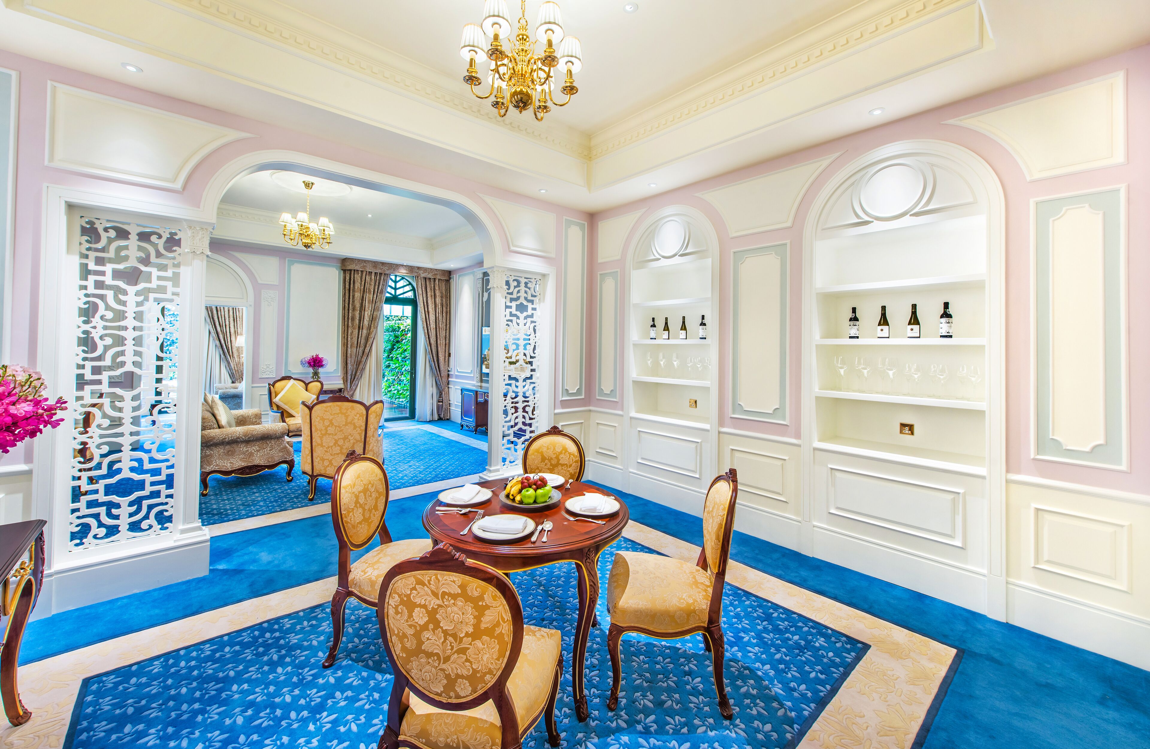 A luxurious dining area with a round table, chairs, and a chandelier.