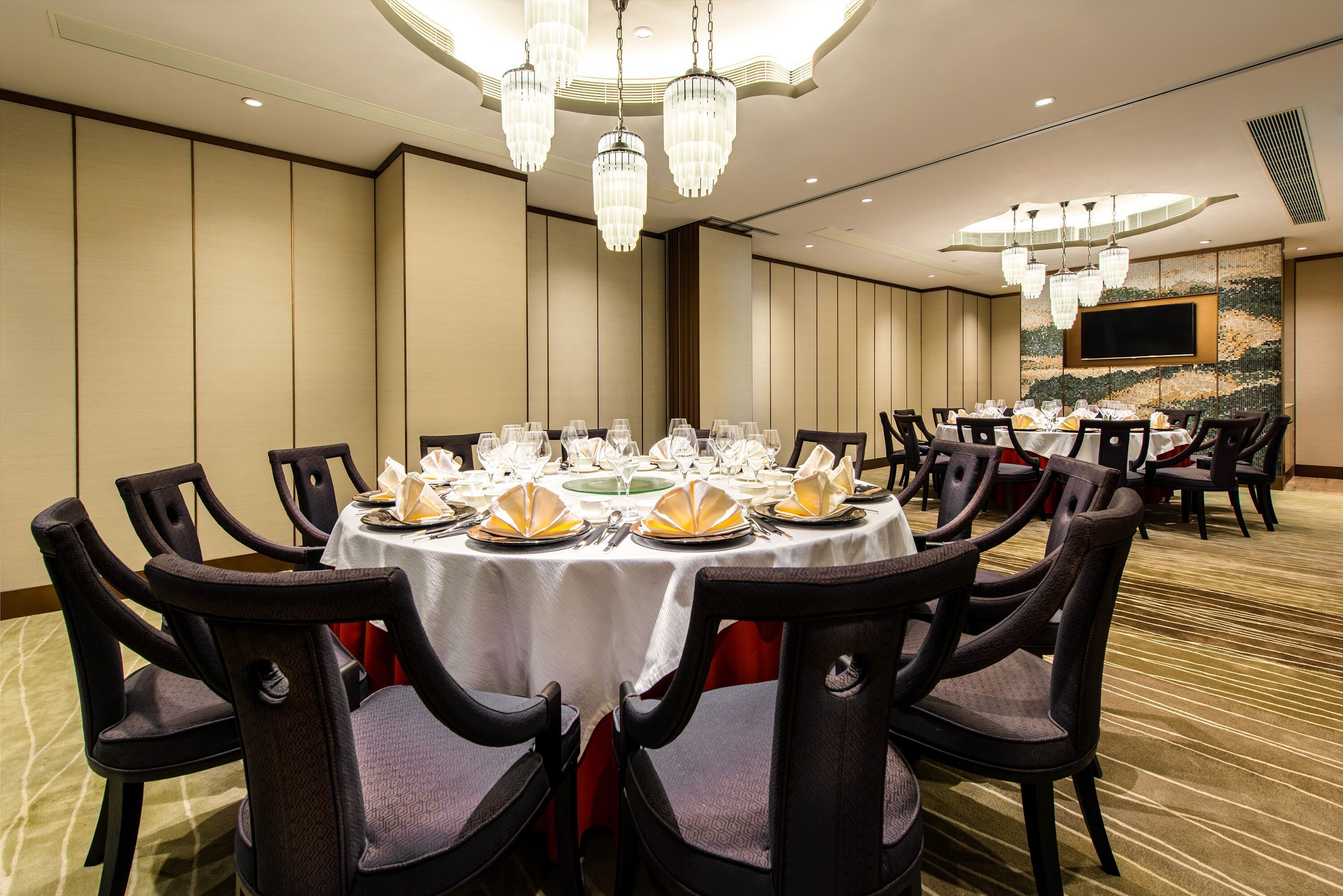 Un salón de banquetes con mesas redondas, sillas y candelabros.