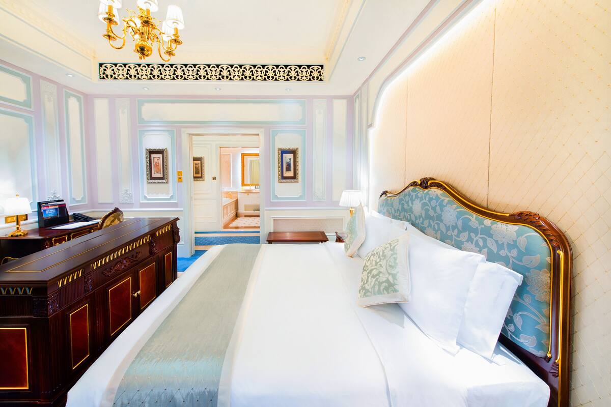A spacious bedroom with a large bed, a dresser, and a vanity.