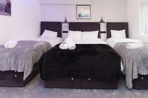 Habitación de hotel con tres camas, cada una con un estilo diferente de ropa de cama.