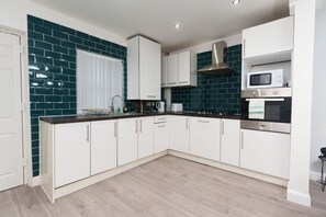 Una cocina moderna con armarios blancos, encimera negra y salpicadero de azulejos azul oscuro.