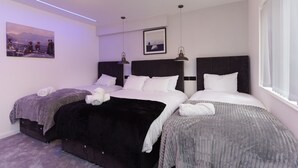 A hotel room with two beds, a large window, and artwork on the walls. - Fewston House Apartments (Leeds)
