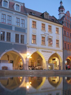 A historic building with arched entrances, a sign reading "HOTEL FRENZELHOF," and a reflection in the water. - Gotikhotel Frenzelhof (Görlitz)