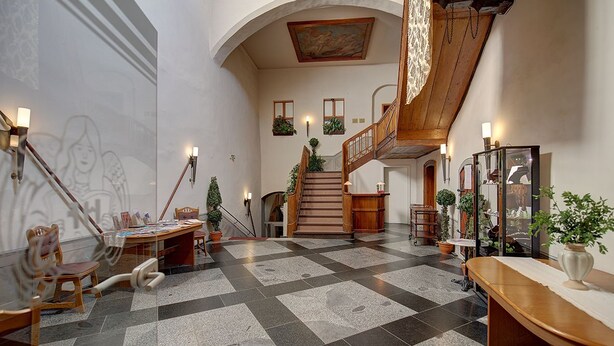 A spacious lobby with a checkered floor, a staircase, and wooden furniture. - Gotikhotel Frenzelhof (Görlitz)