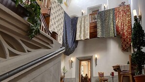 A grand staircase with a red carpet, leading to a landing with a wooden chair and a small table. - Gotikhotel Frenzelhof (Görlitz)