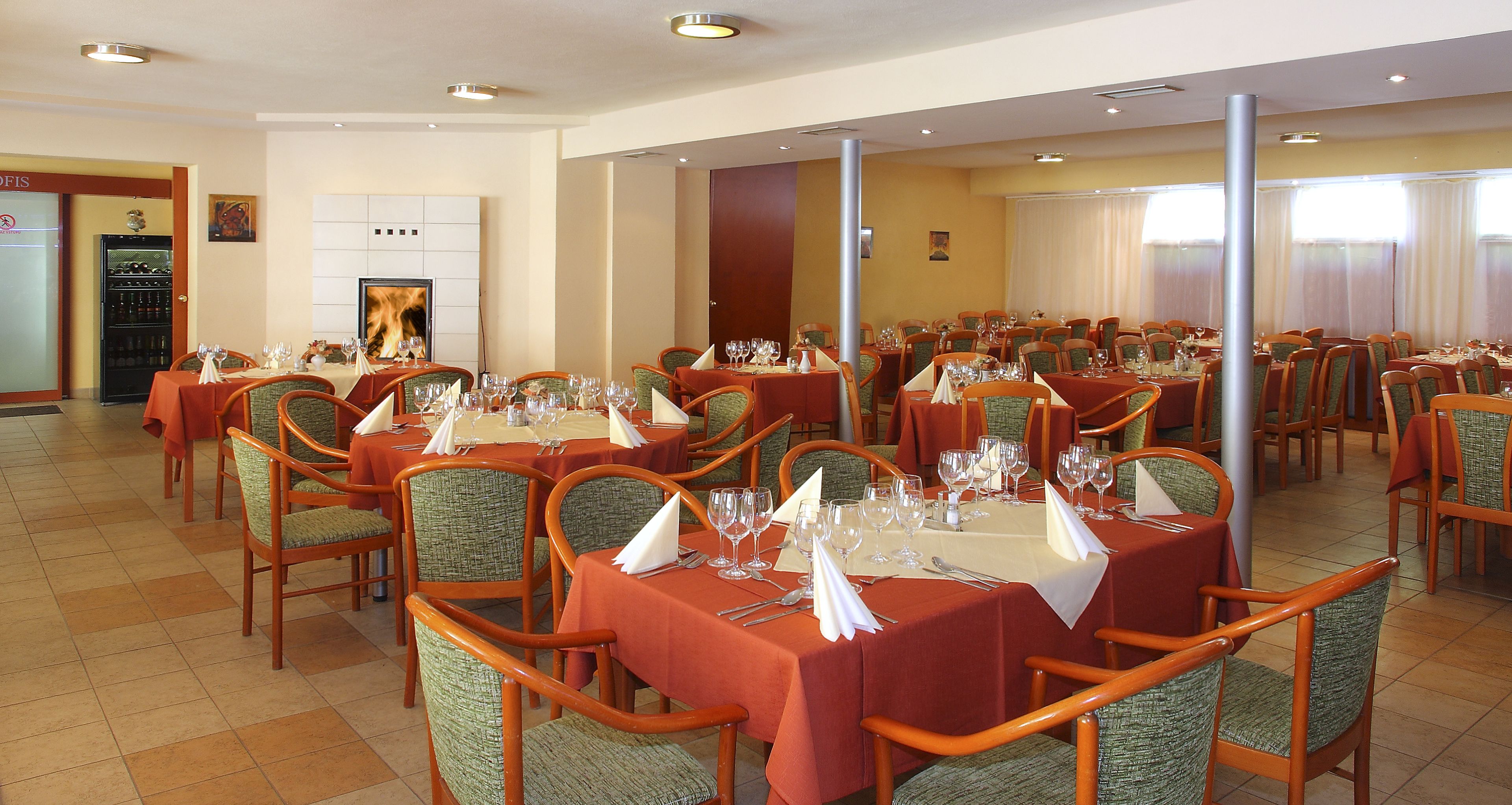 A restaurant with multiple tables set for dining, equipped with chairs and table settings.