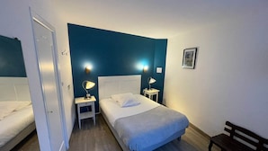 A hotel room with a bed, two bedside tables with lamps, a bench, and a door. - Hotel du Chateau (Vitre)