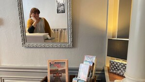 A wooden shelf with books and a framed picture, a mirror, and a lamp on a wall. - Hotel du Chateau (Vitre)