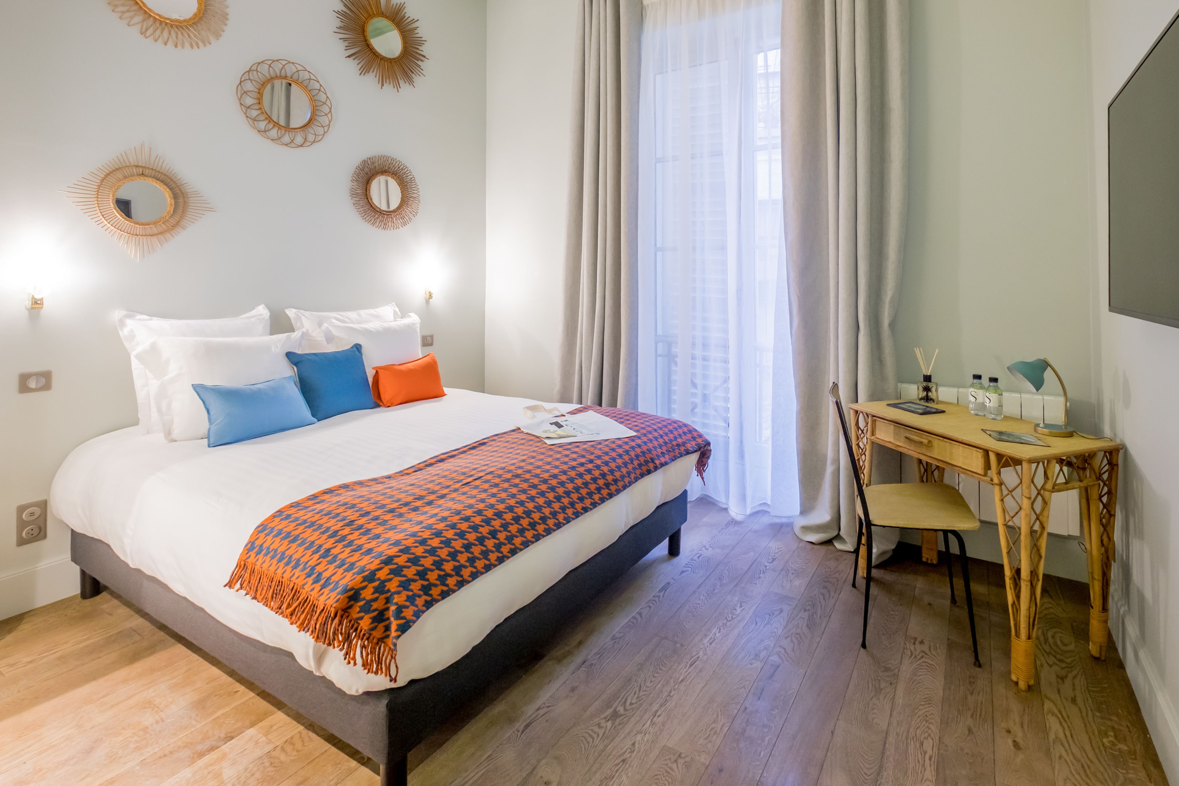 A neatly arranged bedroom with a bed, bedside table, and a desk with a chair.