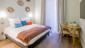 A neatly arranged bedroom with a bed, bedside table, and a desk with a chair.