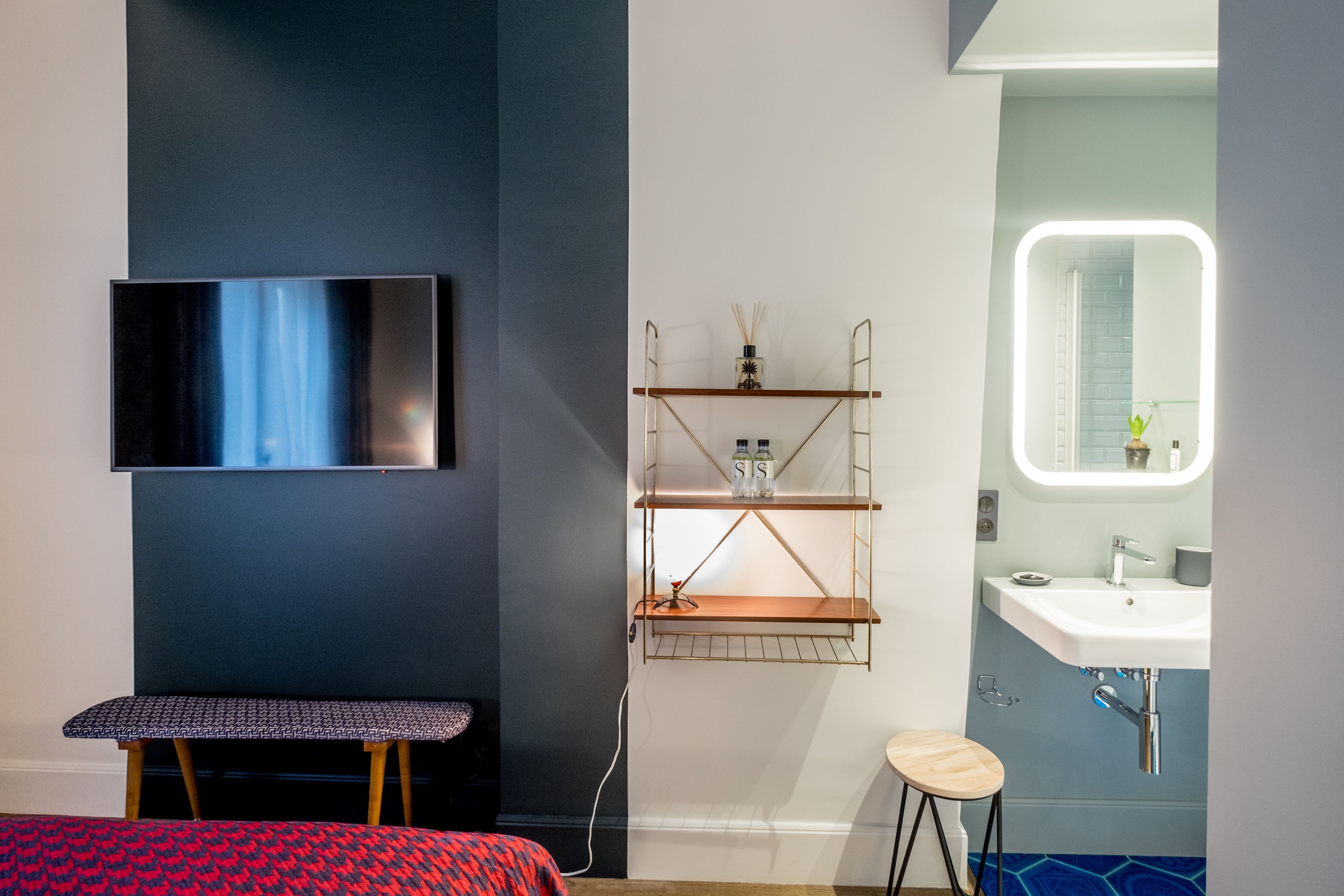 Un baño moderno con un espejo grande, un lavabo y un banco.