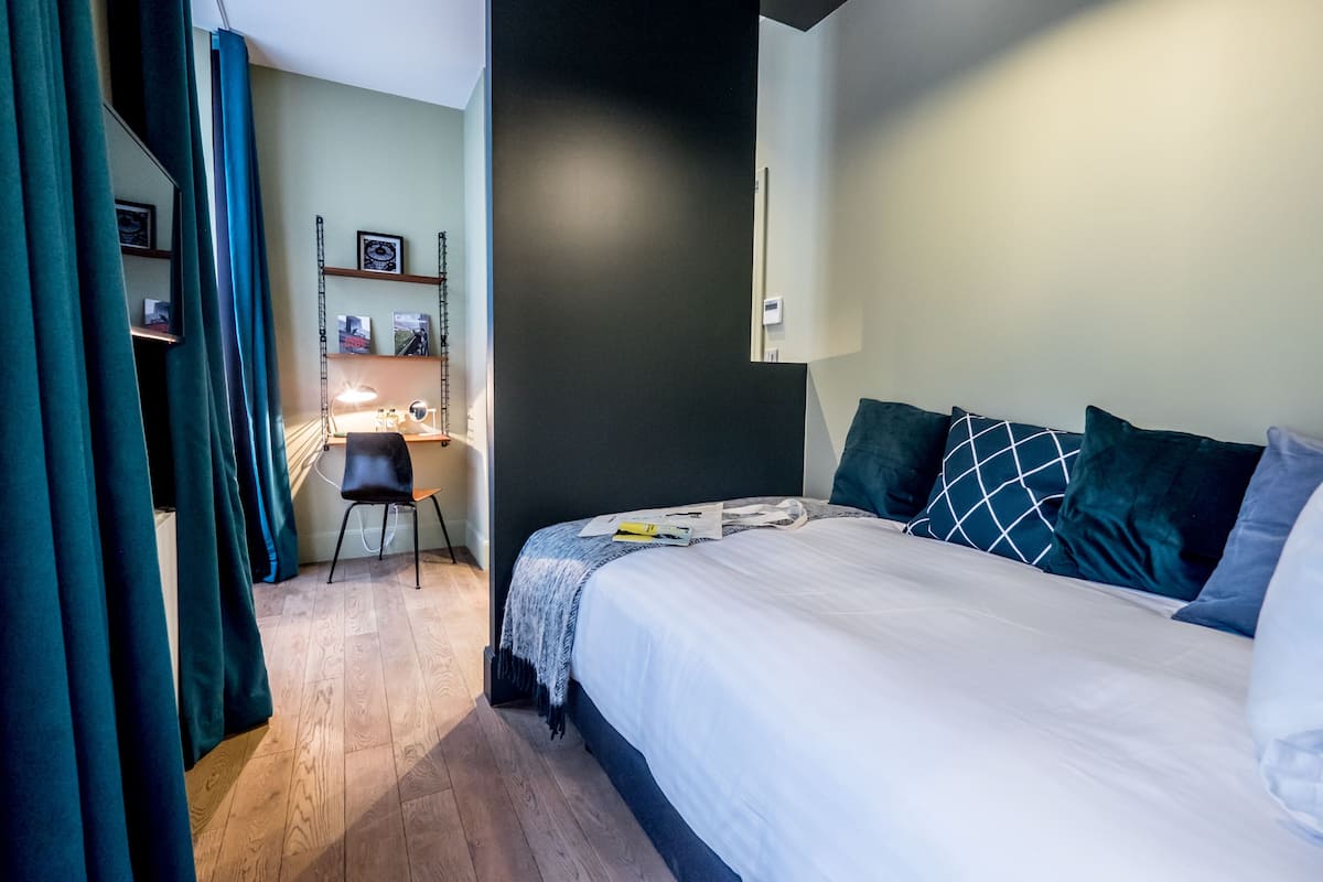 A bedroom with a bed, a desk, and a chair.