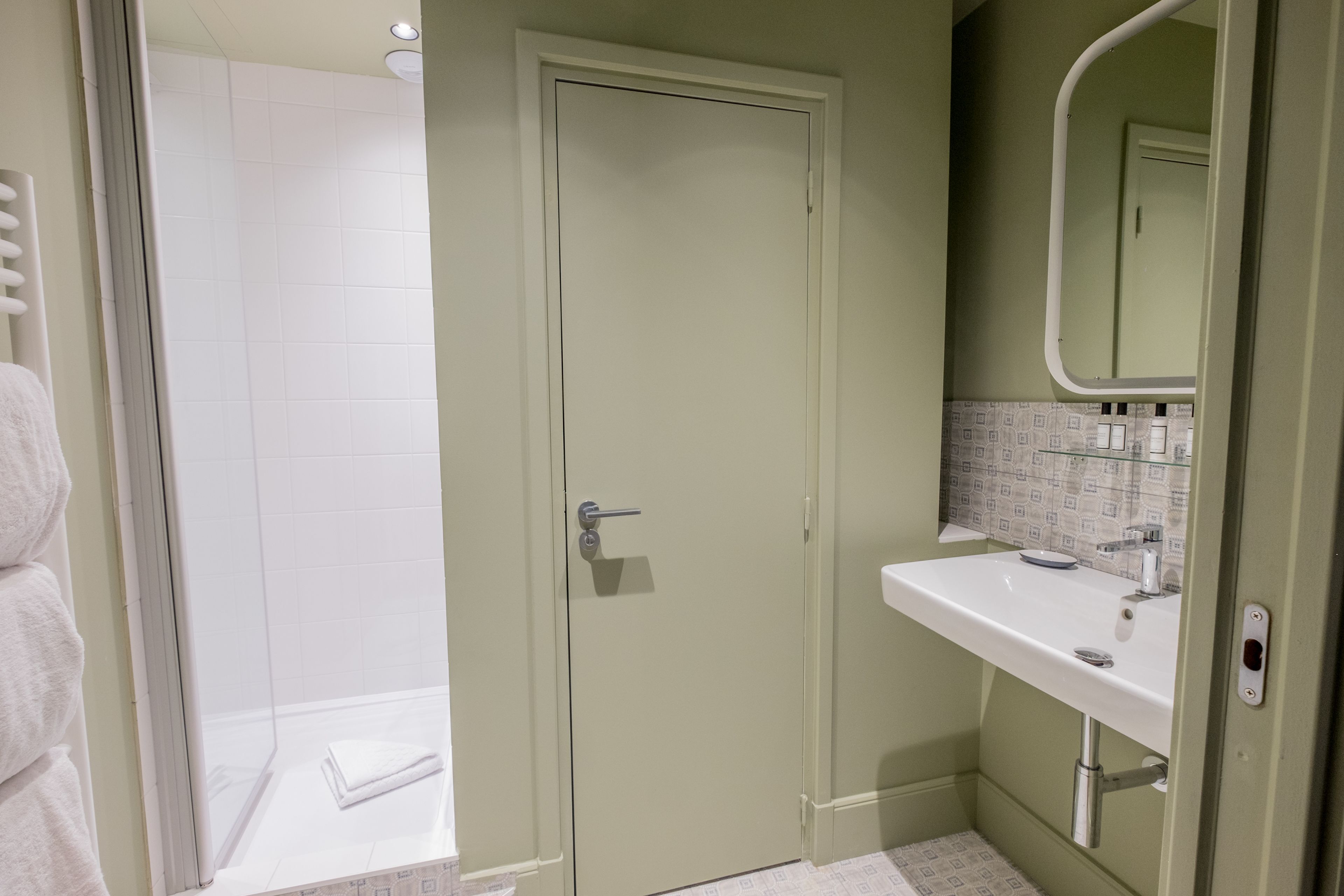 Une salle de bain avec une douche, un lavabo et un miroir.