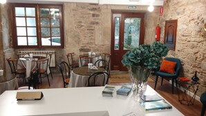 A cozy room with stone walls, wooden furniture, and a clear view of the outside through a window.