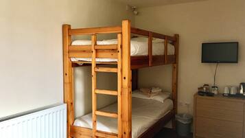 A bunk bed with a TV on the wall, a radiator, and a small dresser with drawers.