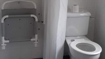 A bathroom with a white toilet, a shower curtain, and a grab bar.
