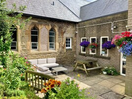 A stone building with a garden patio, a wooden bench, and a white sofa.
