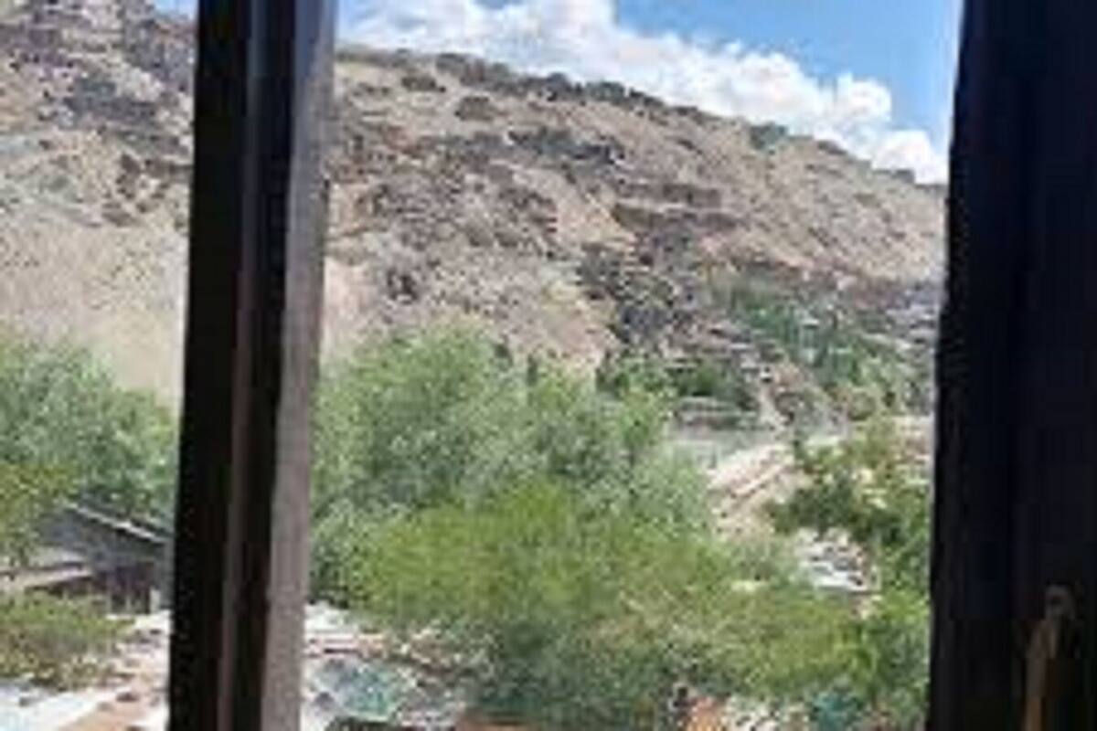 A mountainous landscape with a view of a valley and a building in the distance.
