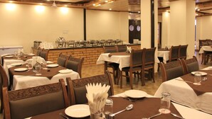 Un restaurante con varias mesas dispuestas para comer, que presenta una pared de ladrillo y techo de madera.