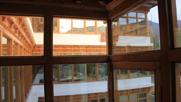 Habitación con amplios ventanales y vigas de madera, con vistas a un paisaje montañoso.