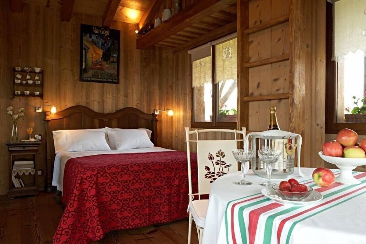 A wooden room with a bed, a table with fruit, and a poster on the wall.