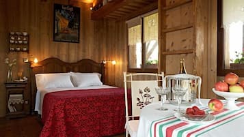 Ein Zimmer mit Holzboden, einem Bett, einem Tisch mit Früchten und einem Poster an der Wand.