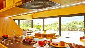 A modern kitchen with a large window, wooden cabinetry, and a dining area with a round table. - Las casas de Ea Astei (Ea)